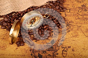 Coffee Beans and Vintage Compass with  magnifying glasson an old world map - trade and explorer concept