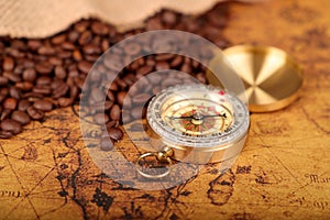 Coffee Beans and Vintage compass on an old world map - trade and explorer concept