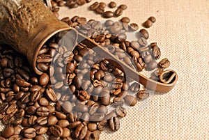 Coffee beans and vintage copper turkish coffee pot (cezve or ibrik) on the cloth sack photo