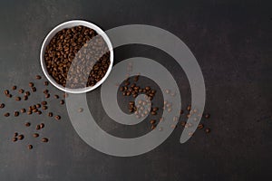 Coffee beans in the white bowl. Top view. on dark stone background