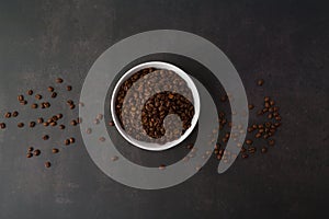 Coffee beans in the white bowl. Top view. on dark stone background