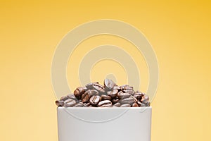 Coffee beans in white cup isolated on yellow background