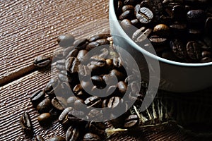 Coffee beans in a white cup over the wooden surface