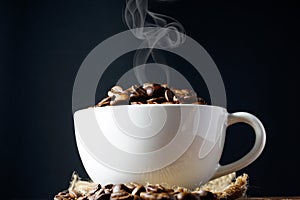 Coffee beans in a white cup over the wooden surface