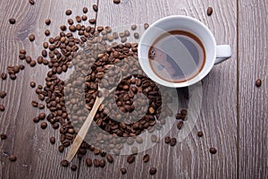 Coffee beans and white cup on wooden background