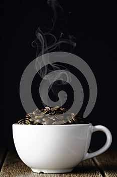 Coffee beans in a white cup on a wooden surface