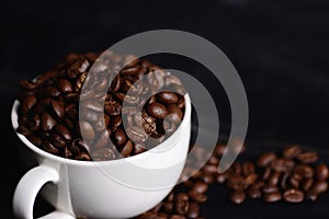 Coffee beans and white mug isolated on black leather background