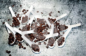 Coffee Beans and white porcelain spoons on a concrete table