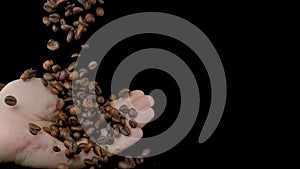 The coffee beans will fall into the hand on a black background. Super slow-motion.