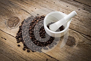 Coffee beans on wooden background and white mortar