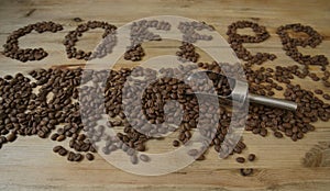 Coffee beans on a wooden background and the word `coffee` from coffee beans