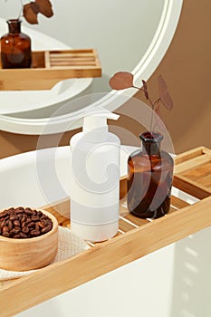 Coffee beans in a wooden bowl, a bottle of shower gel without a label, a brown vase are displayed on a wooden tray. Space inside