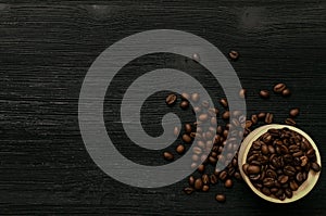 Coffee beans in wooden pot on black wooden table.