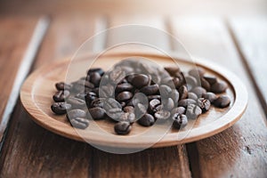 Coffee beans on wooden saucer on the table