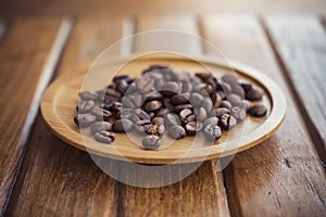Coffee beans on wooden saucer on the table