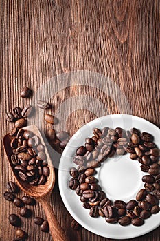 Coffee beans with wooden scoop and saucer