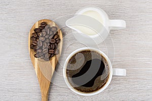 Coffee beans in wooden spoon, milk and cup of espresso
