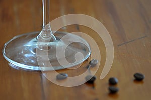 Coffee Beans on a wooden table with the base of a wine glass