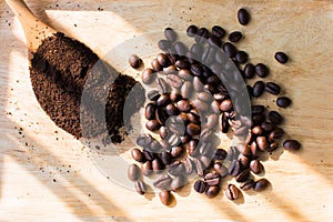 Coffee beans on a wooden tray and coffee grounds on a wooden spoon