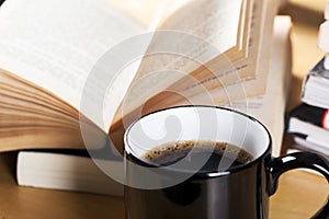 Coffee in black cup and book pile