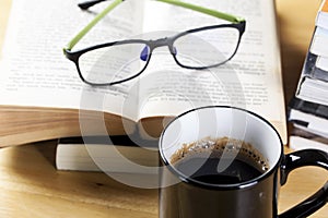 Coffee in black cup and book pile