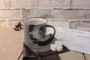 Coffee in a black glass with sugar, against a background of wood and fabric with a newspaper vanilla evening Breakfast