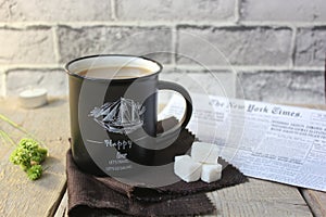 Coffee in a black glass with sugar, against a background of wood and fabric with a newspaper vanilla evening Breakfast