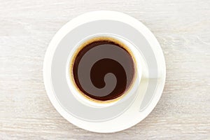 Coffee black hot espresso in white cup, saucer on rustic wooden table background. Top view