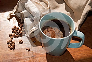 Coffee in blue mug and drought coffee beans in sunshine