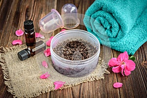 Coffee body scrub, sugar and coconut oil, essential oils, massage vacuum jars on dark wooden rustic table with pink flowers