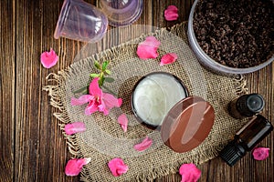 Coffee body scrub, sugar and coconut oil, essential oils, massage vacuum jars on dark wooden rustic table with pink flowers