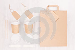 Coffee branding identity mockup - set of two brown paper cups with blank bag, label, cap, sugar on white wood board, top view.