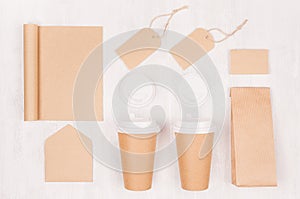Coffee branding identity mockup - set of two brown paper cups with blank notebook, label, card, cap, envelope, packet on wood.