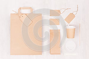 Coffee branding mockup - brown paper cup with blank bag, packet, label, cap, card, sugar on white wood board, top view.