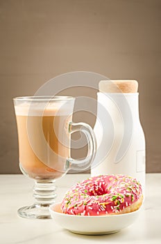 Coffee break: cappuccino, fresh sugary pink donut and white bottle/Coffee break: cappuccino, fresh sugary pink donut and white