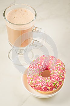 Coffee break: cappuccino glass with fresh sugary pink donut/Coffee break: cappuccino glass with fresh sugary pink donut over white