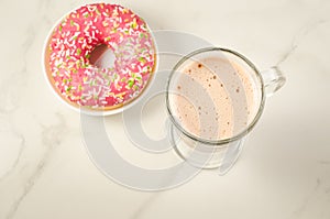 Coffee break with fresh sugary pink donut/Coffee break with fresh sugary pink donut over white marble background. Top view and co