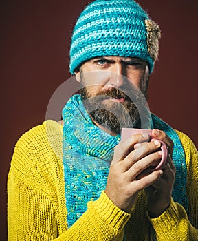 Coffee break. Handsome bearded man with cup of coffee. Portrait of serious man in knitted hat and scarf drinking hot