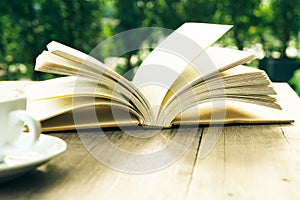 Coffee break and open book on wooden table