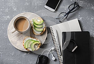 Coffee break during working hours. Flat lay business workplace with notebook, tablet, phone, glasses. Coffee and sandwich with cre