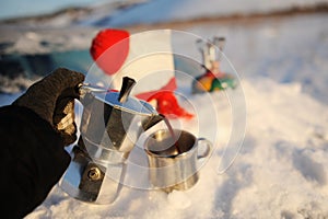 Coffee brewing in moka pot on a gas burner on the car trunk outdoor in winter snow landscape