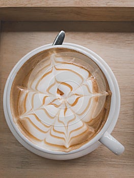 Coffee and bubble in white coffee cup and saucer with spoon on wooden background.top view.flay lay. top down