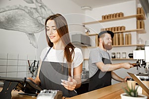 Coffee Business Concept - Beautiful female barista giving payment service for customer with credit card and smiling