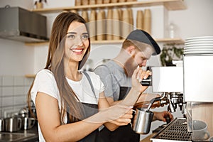 Coffee Business Concept - portrait of lady barista in apron preparing and steaming milk for coffee order with her photo