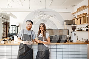 Coffee business concept - portrait of small business partners standing together at their coffee shop
