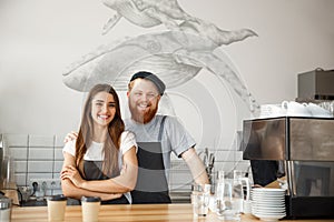 Coffee Business Concept - Positive young bearded man and beautiful attractive lady barista couple enjoy working together