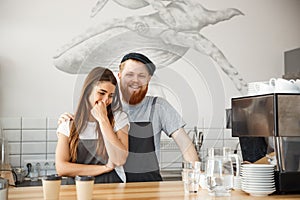 Coffee Business Concept - Positive young bearded man and beautiful attractive lady barista couple enjoy working together