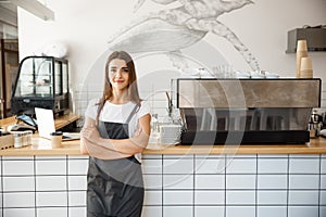 Coffee business owner concept - portrait of happy attractive young beautiful caucasian barista in apron smiling at