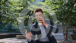 Coffee businessman laughing message looking smartphone on sunny street close up.