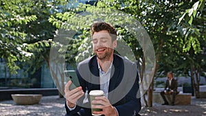 Coffee businessman laughing message looking smartphone on sunny street close up.